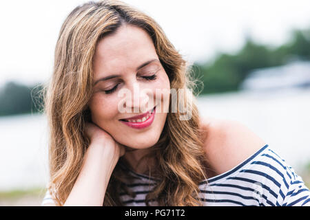 Porträt der lächelnde Frau am Flußufer Stockfoto