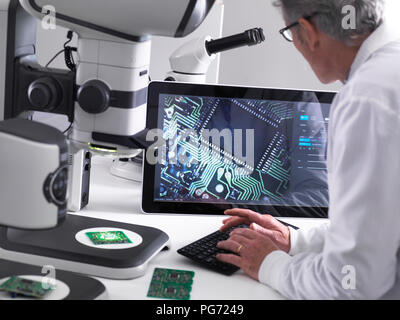 Techniker mit Hilfe eines 3-D Stereo Mikroskop für die Qualitätskontrolle in der Herstellung von Platinen für die Elektronikindustrie Stockfoto
