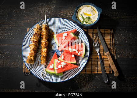 Souvlaki, gegrilltem Schweinefleisch Fleischspieße, Wassermelone, Feta und Knoblauch Creme Stockfoto