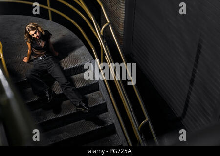 Stilvolle Junge Frau sitzt auf der Treppe bei Nacht Stockfoto