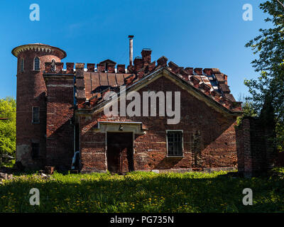 Die Fassade des Gebäudes der alten Stallungen des Rot gebrannten Ziegeln mit einem runden Turm mit Zinnen versehene Dach und Anhänge im englischen Stil auf einem Green Glade i Stockfoto