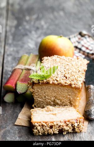 Hausgemachte Apfelkuchen mit Rhabarber Marmelade gekrönt und gesüßte Hafer auf hölzernen Tisch Stockfoto