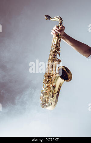 Hand auf die jungen Musiker mit Saxophon in Rauch auf Grau Stockfoto