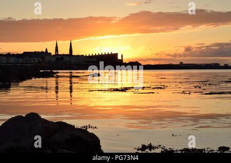 Sonnenuntergang hinter dem Küstenort Dun Laoghaire-Holyhead, County Dublin, Irland. Von der untergehenden Sonne Sonnenlicht spiegelt sich in der Irischen See. Stockfoto