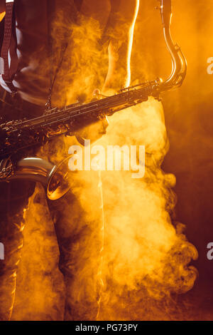 7/8 shot der jungen Musiker mit Saxophon in Rauch Stockfoto