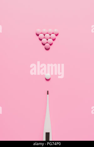 Blick von oben auf die Pillen mit elektrischen Thermometer in Billard Zusammensetzung auf Rosa angeordnet Stockfoto