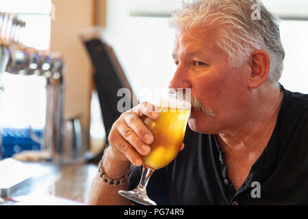 Schöner Mann schmeckt ein Glas Micro Brew Bier. Stockfoto
