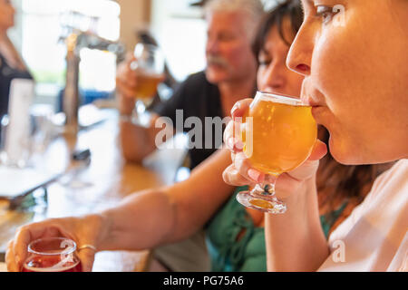 Weibliche schlürfen Glas Micro Brew Bier an der Bar mit Freunden. Stockfoto