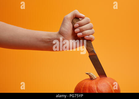 7/8 Schuß von Person, Messer und Schneiden reif Kürbis isoliert auf Orange Stockfoto