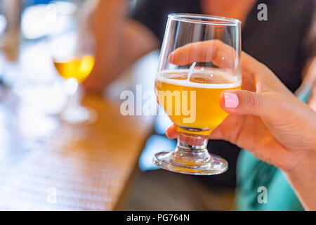 Weibliche Hand Glas Micro Brew Bier an der Bar. Stockfoto