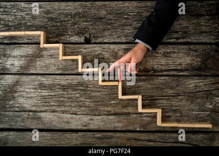 Geschäftsmann oder Studenten zu Fuß seine Finger auf hölzernen Stufen, ähnlich einer Treppe im rustikalen hölzernen Brettern in einem konzeptionellen Bild der persönlichen Eine montiert Stockfoto