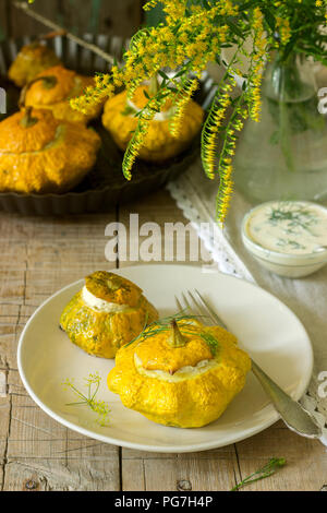 Pattypan Squash oder Kürbisse, gefüllt mit Ricotta mit Basilikum und Dill und serviert mit saurer Sahne Soße. Vegetarisches Essen, rustikaler Stil, selektiven Fokus. Stockfoto