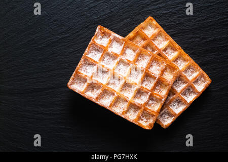 Essen Konzept Klassische quadratische Waffeln mit Puderzucker sugat Toping auf schwarzem Schiefer board Stockfoto