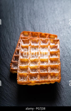 Essen Konzept Klassische quadratische Waffeln mit Puderzucker sugat Toping auf schwarzem Schiefer board Stockfoto