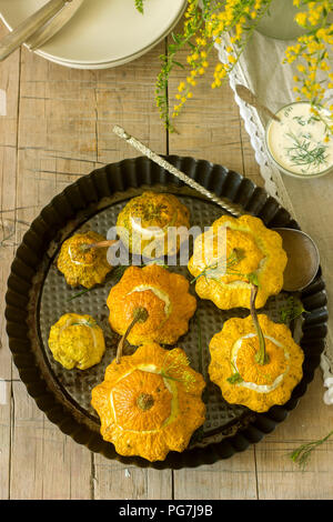 Pattypan Squash oder Kürbisse, gefüllt mit Ricotta mit Basilikum und Dill und serviert mit saurer Sahne Soße. Vegetarisches Essen, rustikaler Stil, selektiven Fokus. Stockfoto