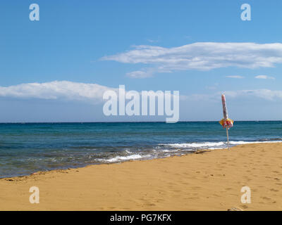 Kalabrien (Italien): einsamer Sonnenschirm an einem einsamen Sandstrand mit einem schlanken Meer und einem blauen Himmel als Hintergrund Stockfoto