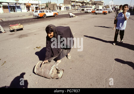 Bagdad, Irak - Oktober 1995 - Eine ältere irakische Frau rollt eine Butan Zylinder in der Straße Markt im Zentrum von Bagdad. Von Irakischen aufgrund der strengen UN-Sanktionen in den 90er kämpfen auferlegt, weil der irakischen Invasion in Kuwait im Jahr 1990. Stockfoto