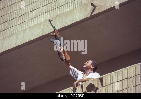 Freudige irakischen Feuern Waffe aus seinem Apartment Block Balkon, in der Feier von Präsident Saddam Hussein überwältigenden Sieg im einzigen Kandidaten Wahlen mit einer einzigen Frage "Möchten Sie von Saddam Hussein als Präsident der Republik genehmigt werden?" "Ja" oder "Nein", Referendum, von denen er 99,6% gewonnen. Stockfoto