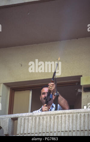 Freudige irakischen Feuern Waffe aus seinem Apartment Block Balkon, in der Feier von Präsident Saddam Hussein überwältigenden Sieg im einzigen Kandidaten Wahlen mit einer einzigen Frage "Möchten Sie von Saddam Hussein als Präsident der Republik genehmigt werden?" "Ja" oder "Nein", Referendum, von denen er 99,6% gewonnen. Stockfoto