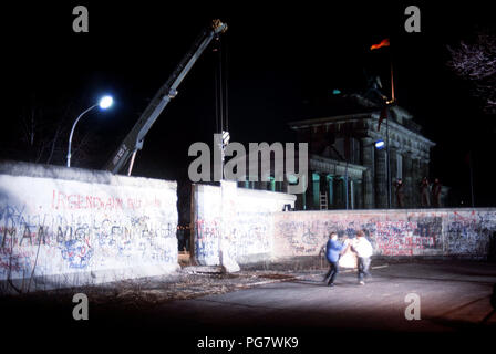 Berliner Mauer 1989 - Anwohner freuen als Kran einen Abschnitt der Berliner Mauer neben dem Brandenburger Tor entfernt. Stockfoto