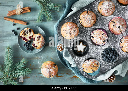 Blueberry Muffins mit Zuckerguss in einem Backblech mit Weihnachtsschmuck rund, flach, Ansicht von oben Stockfoto