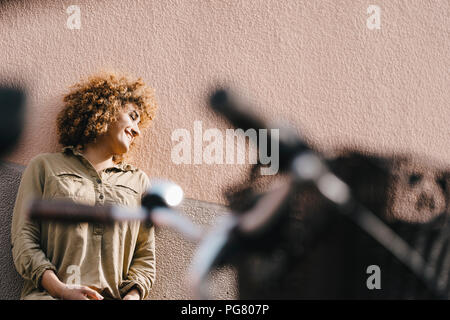 Lachende Frau vor der Hauswand, die Sonne genießen Stockfoto