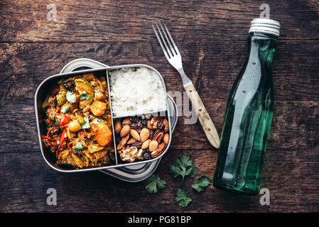 Take Away, tamarind Gemüseeintopf, Karotte, Zucchini, Paprika, Auberginen, Zwiebeln, Tomaten und Falafelkugeln, Reis und Nüsse mit Rosinen Stockfoto