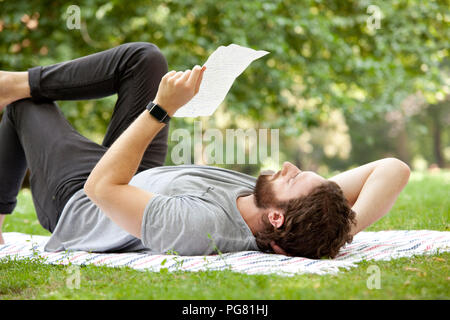 Mann liegen auf Decke in einem Park einen Brief lesen Stockfoto