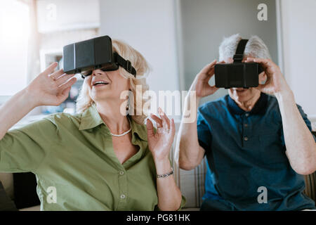 Senior Paar zu Hause sitzen auf der Couch tragen VR-Brille Stockfoto