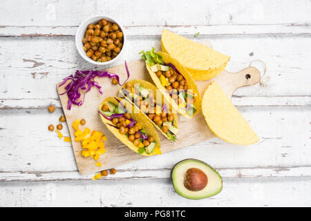 Vegetarische Tacos mit in Curcuma geröstete Kichererbsen, gelbe Paprika, Avocado, Salat und Rotkohl gefüllt Stockfoto