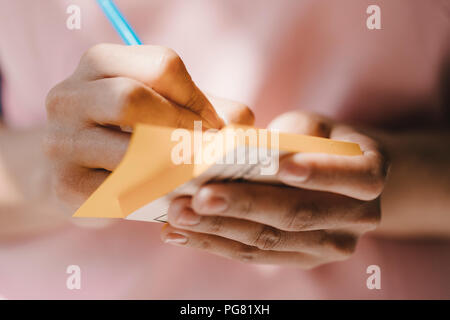 Frau Schreiben mit Stift auf Haftnotizen Stockfoto