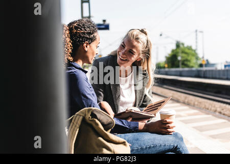 Freunde bei der Verwendung von digital tablet Bahnhof warten Stockfoto