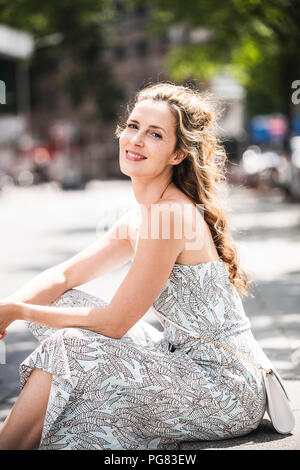 Portrait von lächelnden Frau in der Stadt sitzen Stockfoto