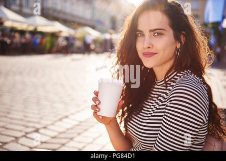 Porträt der schönen jungen Frau mit Kaffee zum Mitnehmen in der Stadt Stockfoto