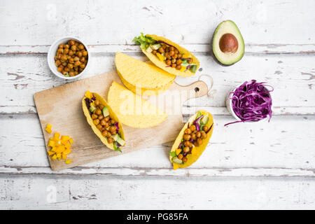 Vegetarische Tacos mit in Curcuma geröstete Kichererbsen, gelbe Paprika, Avocado, Salat und Rotkohl gefüllt Stockfoto