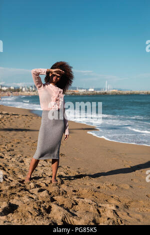 Junge Frau mit Afro Frisur stehen auf dem Strand Stockfoto