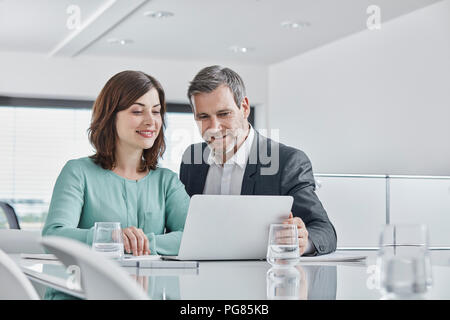Kaufmann und Kauffrau in einer Sitzung im Büro mit Laptops Stockfoto