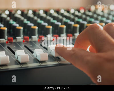 Mann Einstellung Fade Schieberegler auf Audio Mixer im Studio im Innenbereich Stockfoto