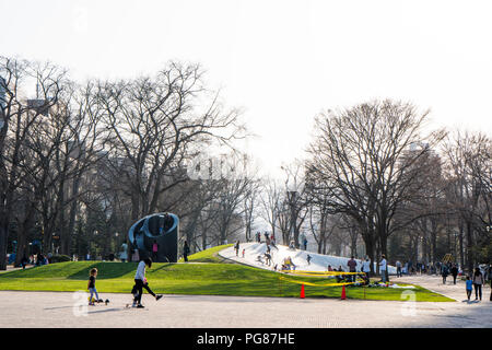 Familien, die Spaß an der Odori Park am Abend mit den Eltern spielen mit ihren Kindern und einem motther unterrichten Ihr Kind Skateboard. Stockfoto