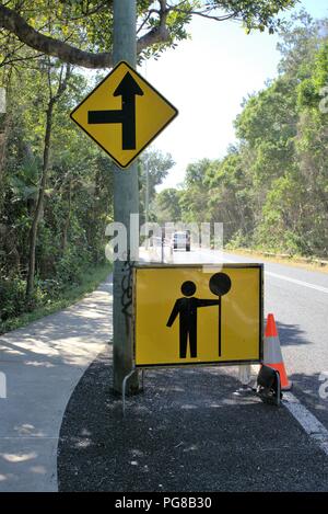 Person, anhalten oder langsamer Schild in Australien. Mann hält street sign für Verkehr änderungen am australischen Stadt Straße. Stockfoto