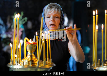 Weibliche Pfarrkind leuchtet eine Kerze in einer Kirche. Beerdigung von Stellvertreter der Menschen der Ukraine Irina Berezhnaya. August 10, 2017. Kiew, Ukraine Stockfoto