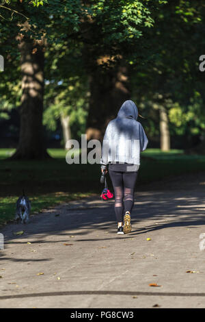 Northampton. Großbritannien 24. August 2018. Eine Frau, die ihrem Hund für einen morgendlichen Spaziergang in Abington Park, die Temperaturen waren in den einzelnen Abbildungen letzte Nacht und heute morgen viel kälter empfinden. Credit: Keith J Smith./Alamy leben Nachrichten Stockfoto