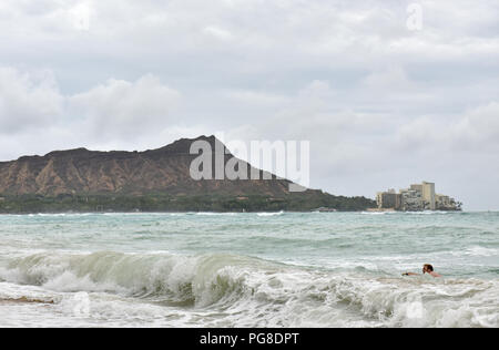 Honolulu, USA. 23 Aug, 2018. Ein Mann surft im Meer am Strand von Waikiki in Honolulu, Hawaii, USA, 23.08.2018. Hurricane Lane, Wetter vorhergesagt als die größte Bedrohung für Hawaii in den Dekaden, gefährlich nah an die Aloha Zustand Donnerstag Morgen verschoben, Auslösen von Heavy Rain, Erdrutsche und Überschwemmungen. Credit: Sun Ruibo/Xinhua/Alamy leben Nachrichten Stockfoto