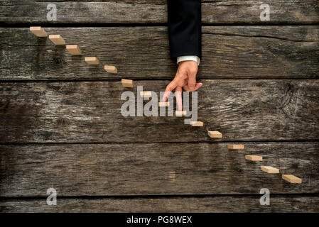 Geschäftsmann seinen Finger nach oben Holz- schritte oder Pflöcke, ähnlich einer Treppe im rustikalen hölzernen Brettern in einem konzeptionellen Bild von Erfolg montiert, Promo Stockfoto