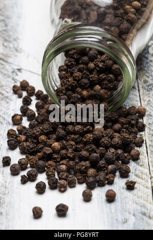 Pfefferkörner in einer Flasche auf Holz. Stockfoto