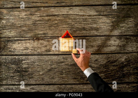 Ansicht von oben von Immobilien oder Versicherung Bau ein Haus aus Holz Würfel, der Platzierung der letzten Stück das Projekt auf rustikalen Schreibtisch zu beenden Stockfoto