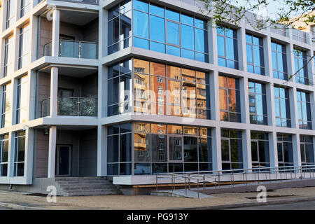 Alte Gebäude in einem Glas fassade eines neuen und modernen Bürogebäude widerspiegelt. Komsomolsk am Amur, Russland Stockfoto