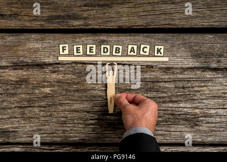 Nicht identifizierbare erwachsenen Mann mit seiner Hand in Position kleine menschliche Figur, Papier bar mit dem Wort feedback. Stockfoto