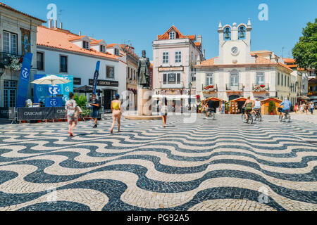 Touristen am zentralen Platz - Praca 5 de Outubro - mit wunderschönem Pflastermuster und Statue des Dom Pedro in Cascais, Portugal Stockfoto