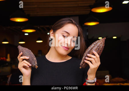 In der Nähe von schönen Frau Holding in den Händen zwei Stücke von cacao Topf und tragen schwarze Kleidung, in der Stadt Banos Ecuador. Stockfoto